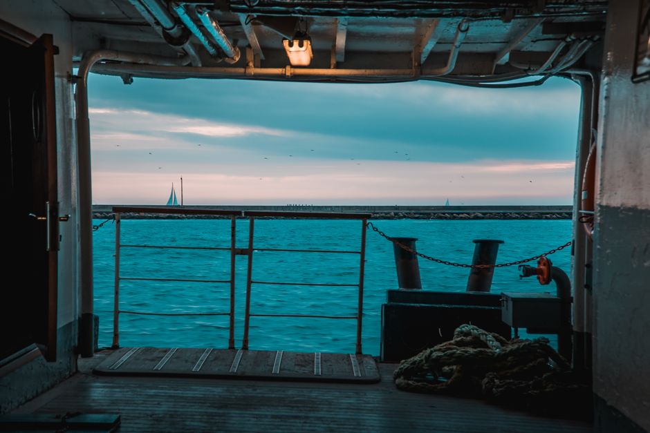 A serene view of the sea from a ferry deck in İstanbul with sailboats on the horizon.