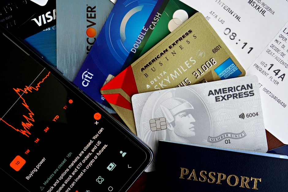 Flat lay of credit cards, passport, and a phone showing stock data, depicting finance and travel.