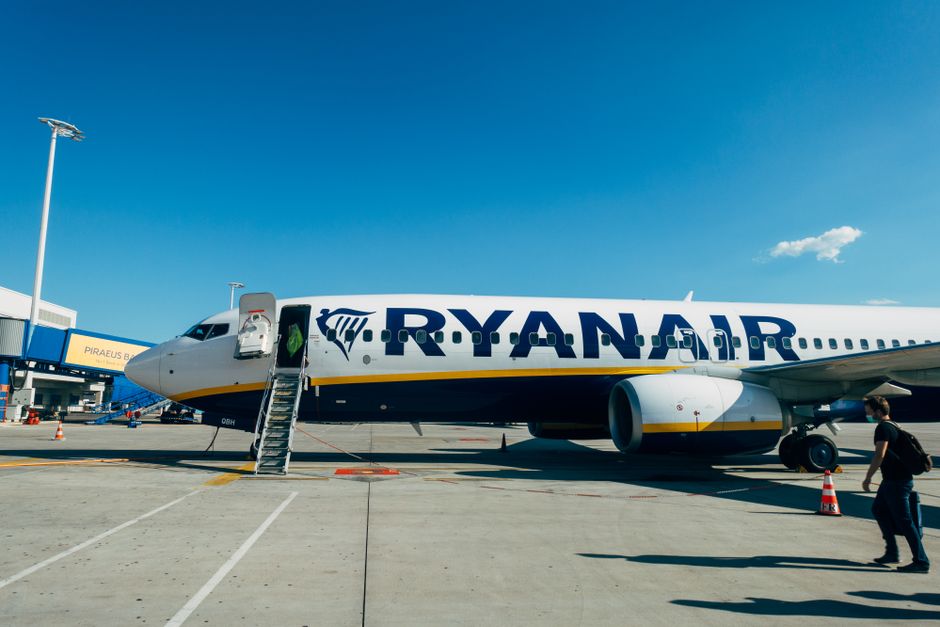 Ryanair airplane parked at airport, with clear blue sky and boarding ladder visible.